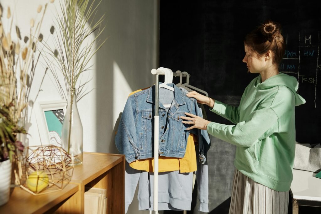 Woman in casual setting selecting clothes from a rack, reflecting a modern indoor lifestyle.