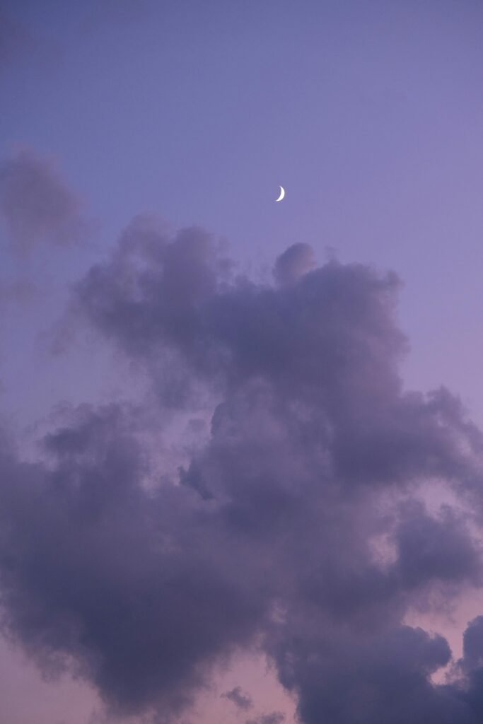 A peaceful twilight sky in Lebanon with clouds and a crescent moon.