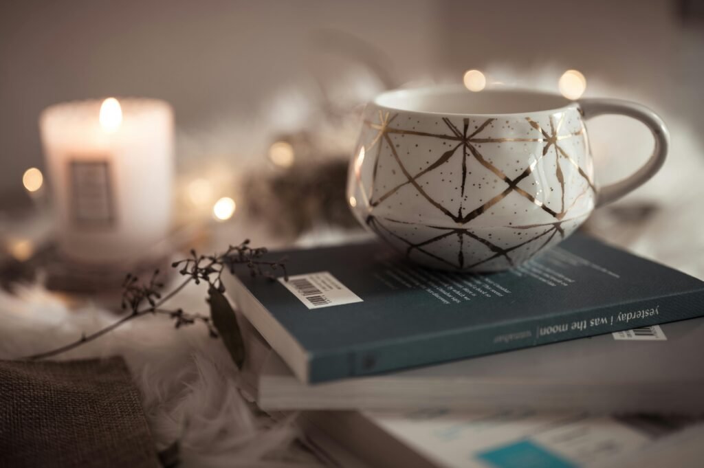 A warm, inviting scene featuring a decorative cup on books, with soft candlelight and a peaceful ambiance.
